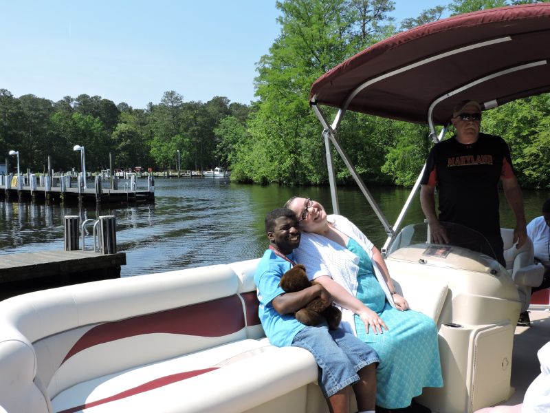 Disabled man with Teddy Bear sitting on Boat Hugging his Personal Care Taker