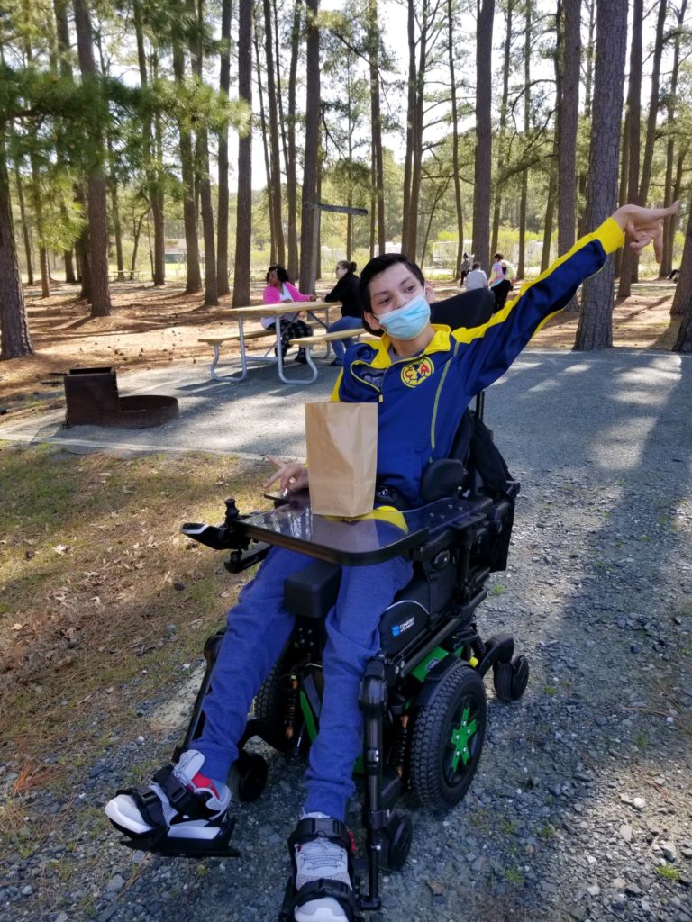Teenage Boy in a Wheel Chair with Lunch Bag in a Park